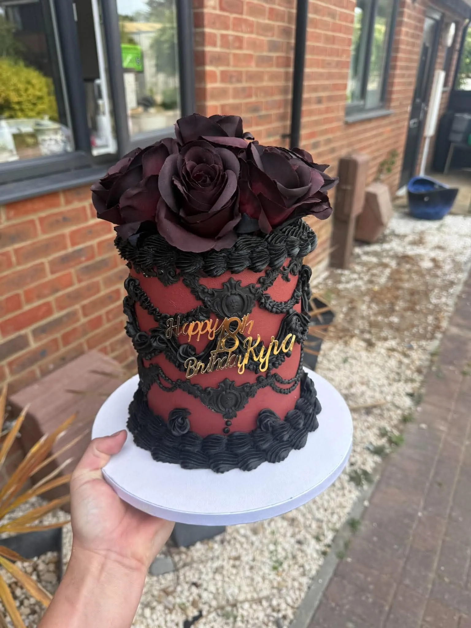 Cake 6: A red and black piped cake topped with dark roses