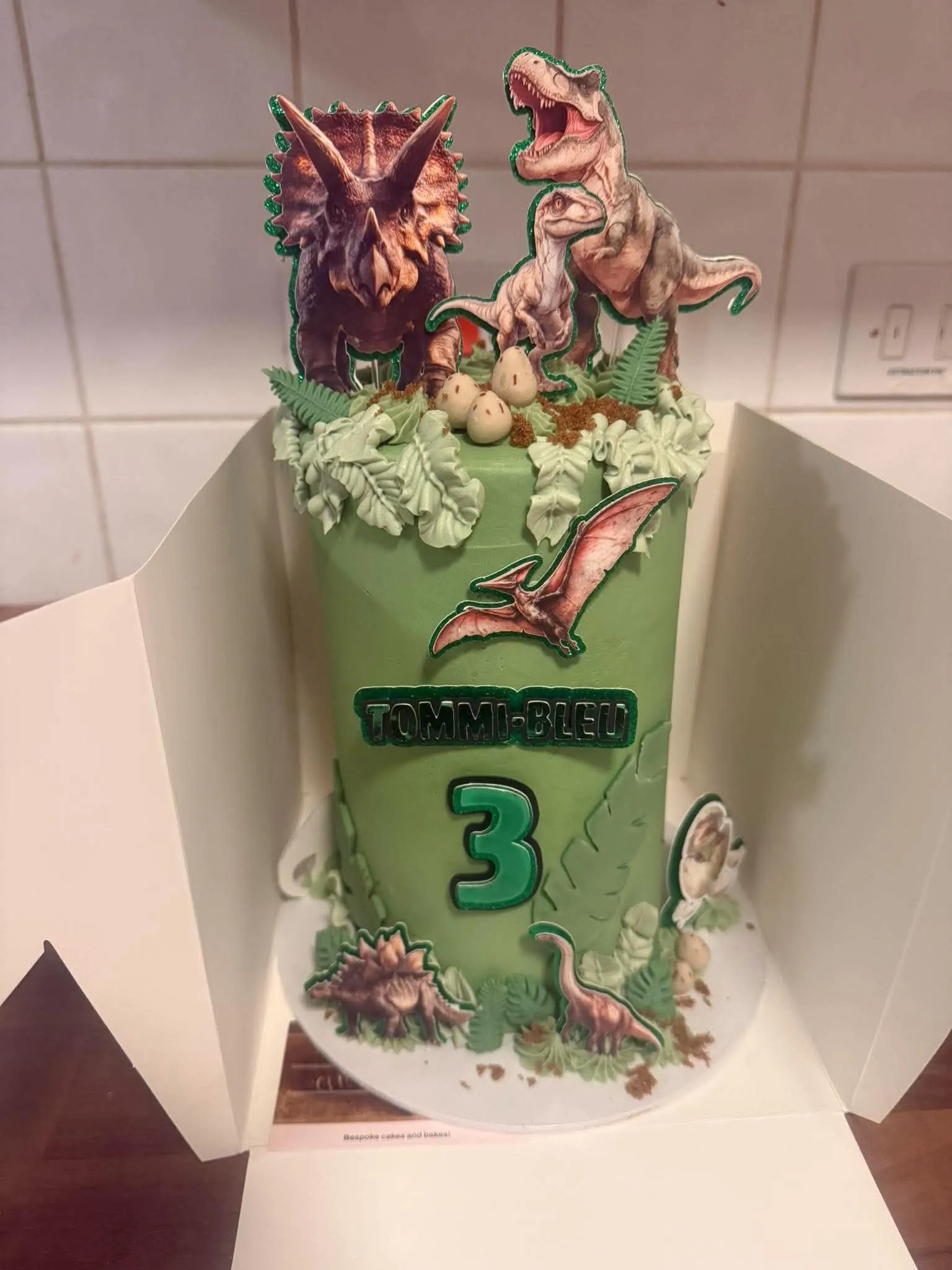 Cake 8: A green dinosaur cake with sculpted foliage, eggs and dinosaur toppers
