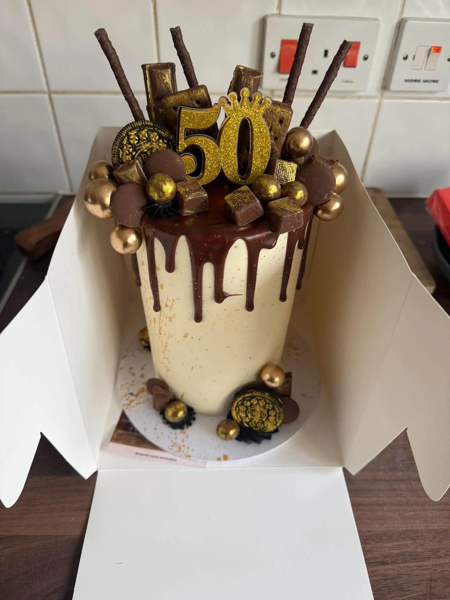 Cake 5: A chocolate drip cake with gold sweets and a gold number 50