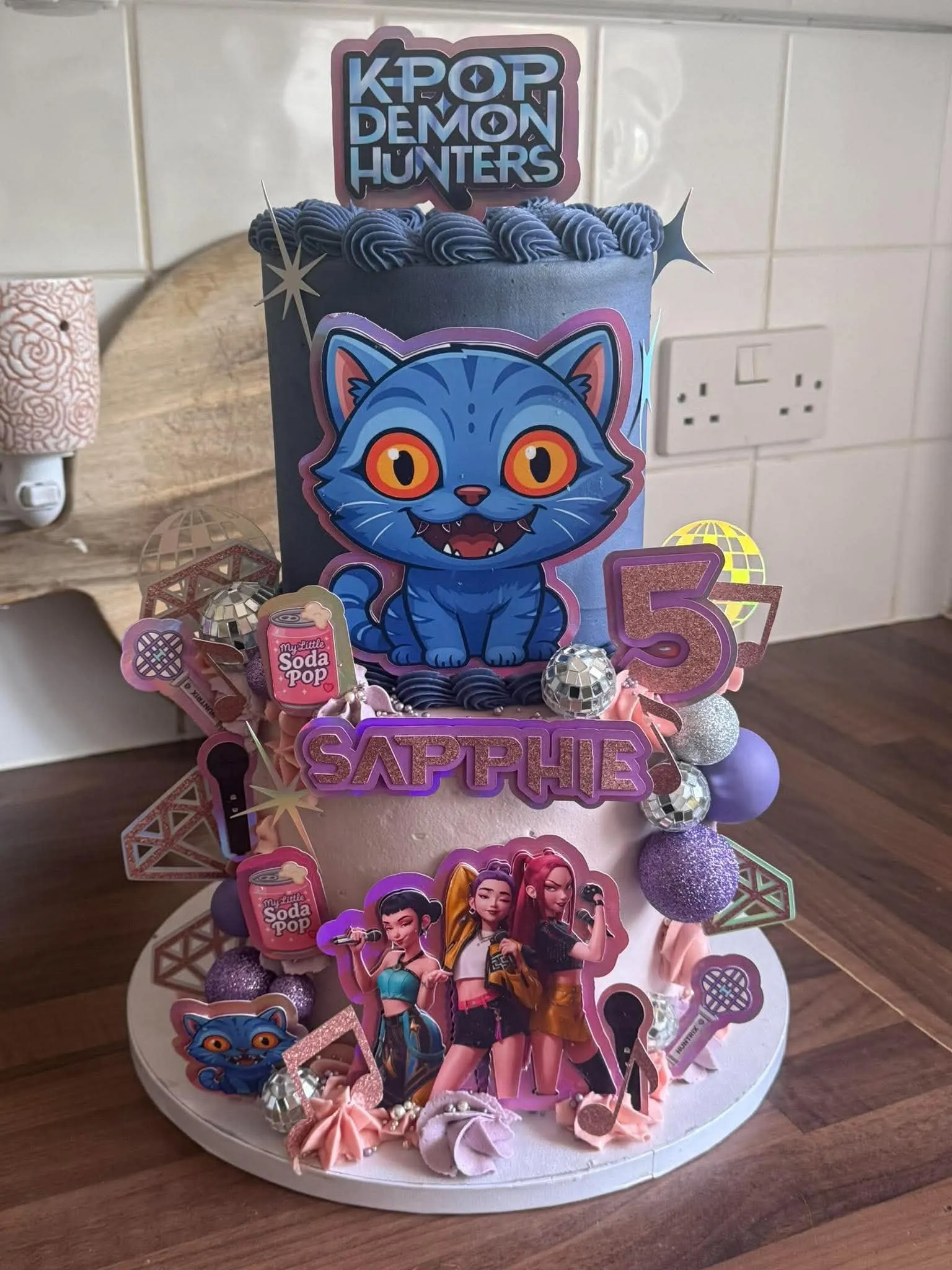 Cake 11: A tall two-tier cake with a blue cat figure, mirrored balls and pink decorations